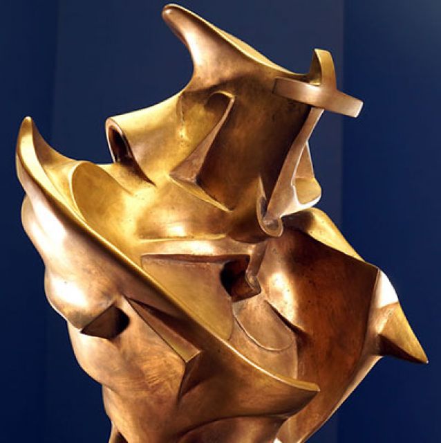  Das Foto zeigt ausschnitthaft die goldglänzende Bronzeplastik Einzigartige Formen der Kontinuität im Raum. Die geschwungenen Formen erinnern an einen gehenden Menschen zugleich aber auch an Maschinenteile und andere Gegenstände